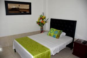 a bedroom with a bed with a vase of flowers at Hotel Las Marias in Puerto López