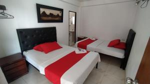 two beds in a small room with red pillows at Hotel Las Marias in Puerto López