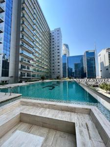 a large swimming pool in a city with tall buildings at 5* Studio, 10min walk to Dubai Mall, 1min Bay Sqr in Dubai