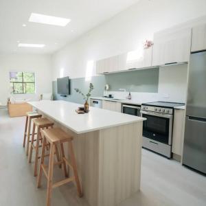 a kitchen with a white counter and stools at Newly Renovated 1 Bedroom Condo in Japantown! Near Gastown & Railtown! in Vancouver