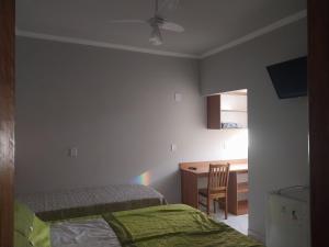 1 dormitorio con cama, escritorio y silla en Hotel-Pousada Quartzo Rosa, en São Thomé das Letras
