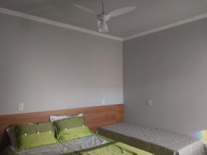 um quarto com 2 camas com almofadas verdes e um tecto em Hotel-Pousada Quartzo Rosa em São Thomé das Letras