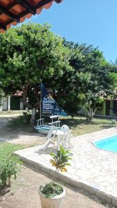 a swimming pool with two chairs and a boat at Pousada Portal dos Coqueirais in Jequia da Praia