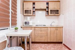 a small kitchen with wooden cabinets and a table at Яркая Квартира на Арбате in Almaty
