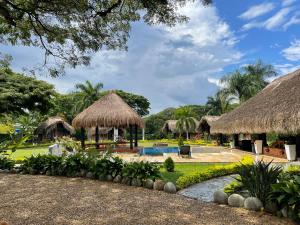 a resort with a swimming pool and thatched huts at finca playa alta in Palmira