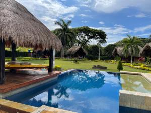a resort with a swimming pool and a thatch roof at finca playa alta in Palmira