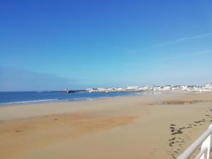 een uitzicht op een strand met voetafdrukken in het zand bij Vue Belle île in Quiberon