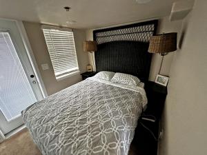 a bedroom with a bed with a white comforter and two windows at Marina Dunes Park Model in Marina
