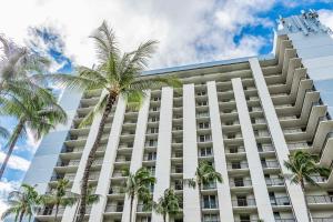a large white building with palm trees in front of it at Hawaiian Princess Makaha in Waianae