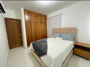 ein Schlafzimmer mit einem großen Bett und einem Holzschrank in der Unterkunft Hermoso apto 804 en Villa María in Santiago de los Caballeros