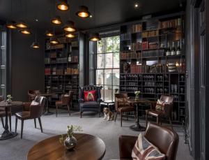 biblioteca con mesas, sillas y estanterías en The Churchill Hotel en York