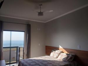 Schlafzimmer mit einem Bett und einem Fenster mit Aussicht in der Unterkunft Hotel-Pousada Quartzo Rosa in São Thomé das Letras