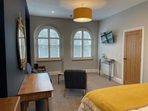 a bedroom with a bed and a desk and windows at Rooms at Allium in Tenby