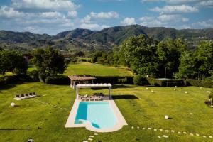 an outdoor swimming pool in a field with mountains in the background at Tenuta il Giardino in Capannori