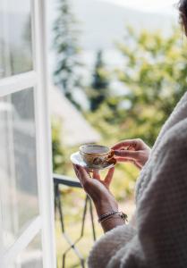 une femme tenant un bol devant une fenêtre dans l'établissement Villa Mavro Mavrovo, à Mavrovo