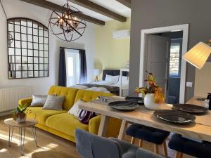 a living room with a yellow couch and a table at FRIDA Apartman, Exkluzív várpanorámával, a belváros szívében in Veszprém