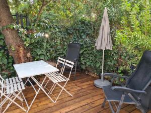 una mesa con sillas y una sombrilla en una terraza de madera en Les chênes verts, en Sommières