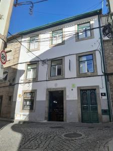 a white building with green doors on a street at Covilhã Hostel in Covilhã