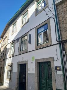 a white building with green doors on a street at Covilhã Hostel in Covilhã
