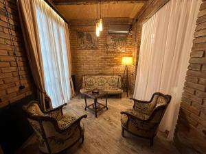 a living room with two chairs and a table at Сity center Loft style Apartment in Tbilisi City