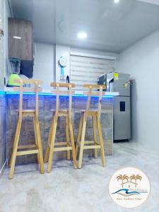 a kitchen with three wooden stools at a counter at Apartamentos Mar & Arena in San Andrés