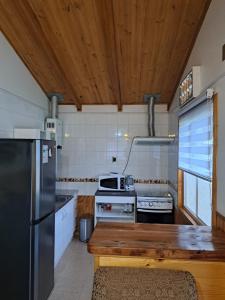 cocina con techo de madera y nevera en Cabañas Robinson, en Puerto Puyuhuapi