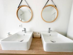twee wastafels in een badkamer met twee spiegels aan de muur bij Tiam Anh-TiAM CONCIERGERIE DISNEY Maison PARKING Gratuit in Bailly-Romainvilliers