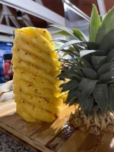 a pineapple on a wooden cutting board next to a plant at Raintree Gardens - 1 Acre, Ocean Views, Steps from beach in Matei
