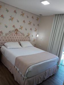 a bedroom with a large bed with a white bedspread at Pousada Serrano in Campos do Jordão