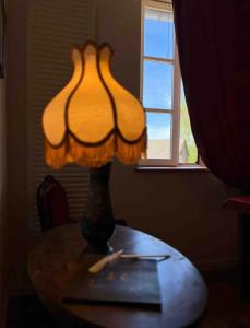 una lámpara sentada en una mesa frente a una ventana en Chez Vanessa, en Saint-Gervais-dʼAuvergne