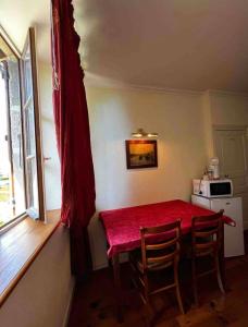 cocina con mesa roja con sillas y microondas en Chez Vanessa, en Saint-Gervais-dʼAuvergne