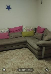 un sofá marrón con almohadas rosas y verdes en شقه مفروشه, en Alejandría