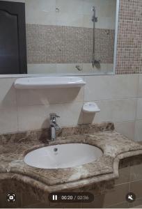 baño con lavabo de mármol y TV en شقه مفروشه, en Alejandría