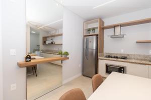 a kitchen with a table and a refrigerator at 139C - lindo apartamento a 50m da praia de Canto Grande in Bombas