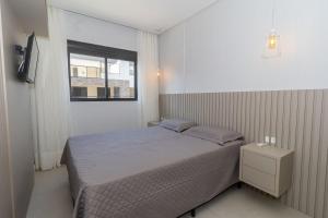a small bedroom with a bed and a window at 139C - lindo apartamento a 50m da praia de Canto Grande in Bombas
