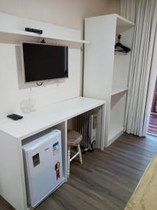 a room with a desk with a tv and a computer at Pousada Serrano in Campos do Jordão