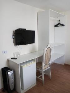 a desk with a tv and a chair in a room at Pousada Serrano in Campos do Jordão