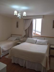 two beds in a hotel room with a window at Pousada Serrano in Campos do Jordão