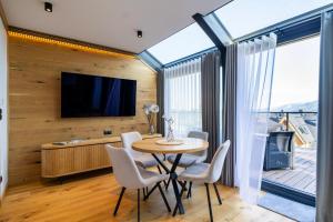 a dining room with a table and chairs and a tv at Apartament Magiczne Podhale by Apart Concept Podhale in Kościelisko