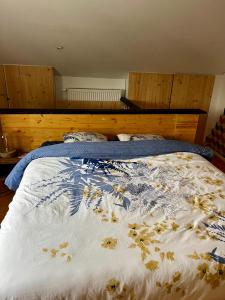 Una cama con una manta con flores. en Capstay La Louvière, en La Louvière
