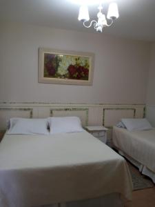 a bedroom with two beds and a painting on the wall at Pousada Serrano in Campos do Jordão