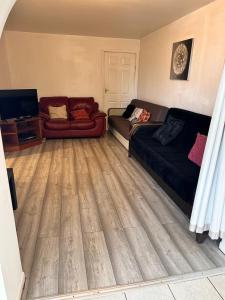 a living room with a couch and a tv at East Lodge - Spacious 4 bed house in Basildon