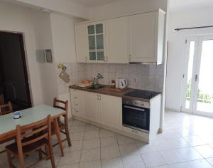 - une cuisine avec des placards blancs, une table et un évier dans l'établissement Apartments Nemo, à Vinišće