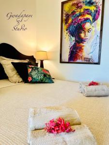 a bed with two towels and a painting on the wall at Vue Exclusive Mer et Volcan, Village Vacances avec Plage et Piscine, Les Gwadastudios in Sainte-Anne