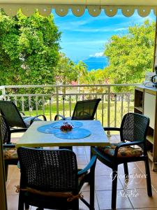 een tafel en stoelen op een patio met uitzicht op de oceaan bij Vue Exclusive Mer et Volcan, Village Vacances avec Plage et Piscine, Les Gwadastudios in Sainte-Anne