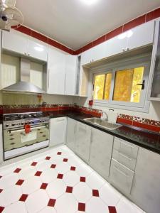 a kitchen with white cabinets and red and white tiles at فيلا اول صف بحر مارينا الساحل الشمالي العلمين برايفت بول in El Alamein