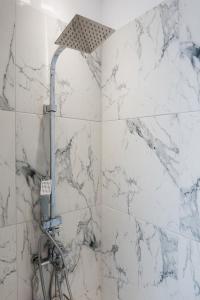 a shower in a bathroom with white marble walls at ELITE APARTMENTS in Thessaloniki