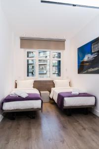 two beds in a room with two windows at ELITE APARTMENTS in Thessaloniki