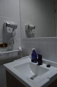 a bathroom sink with a soap dispenser and a mirror at Hotel Rukalaf in Chillán