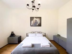 Un dormitorio con una cama con sábanas blancas y una lámpara de araña. en KING Apartments in city centre, en Leópolis